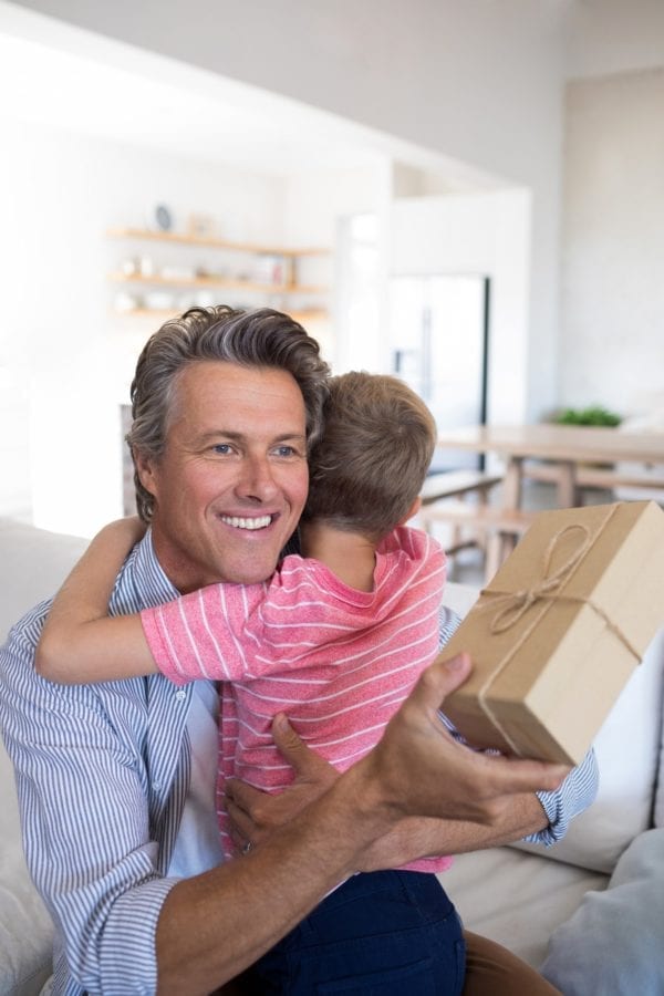 Father embracing son while receiving gift in living room